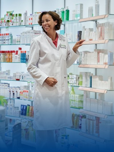 A pharmacist in white work clothes stands next to the medicine shelf.