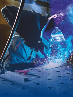Welder in protective clothing welding on iron.