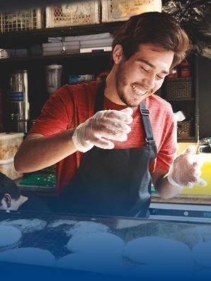 Street food worker wears a chef's apron and a red T-shirt.