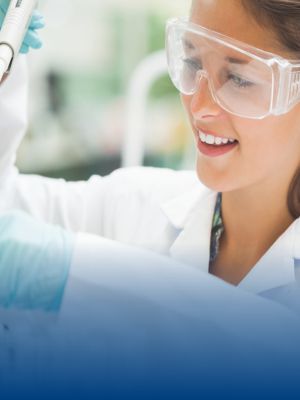 A lab technician wears a lab coat and safety goggles.
