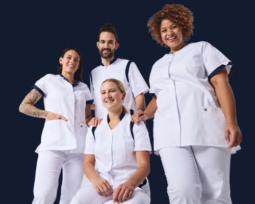 One male and three female carers wear white tunics and work trousers.