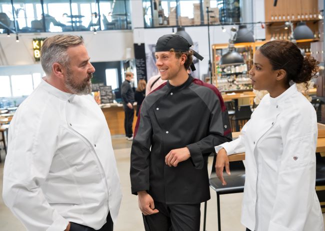 Two men and a woman are wearing restaurant clothes in a restaurant.