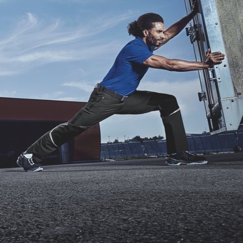 A man supports a difficult object in BP® work clothes.