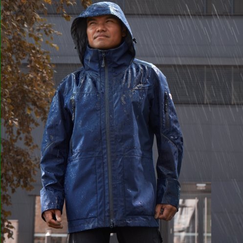 A man wears a BP® workwear rain jacket in rainy weather.