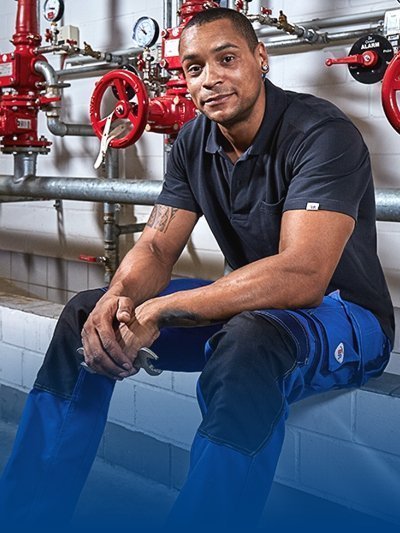 A plumber wears workwear clothing.